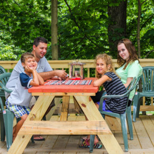 family playing Uno on bench on deck of cabin Indian Head Canoeing Rafting Kayaking Tubing Delaware River