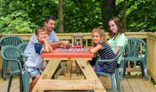 family playing Uno on bench on deck of cabin Indian Head Canoeing Rafting Kayaking Tubing Delaware River