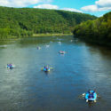 several groups on rafts on Delaware River with green tree views Indian Head Canoeing Rafting Kayaking Tubing Delaware River