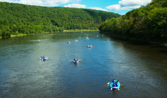 several groups on rafts on Delaware River with green tree views Indian Head Canoeing Rafting Kayaking Tubing Delaware River